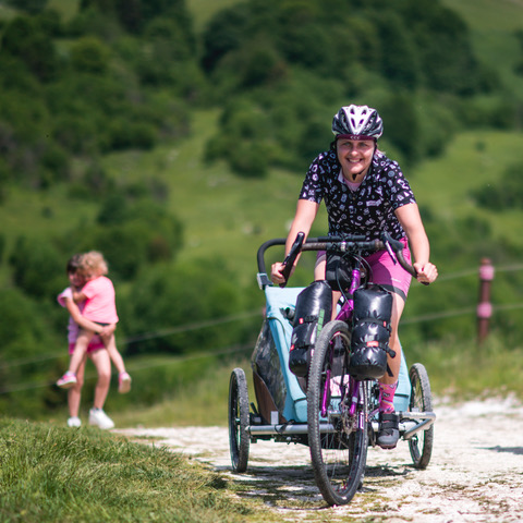 mamma in bicicletta con carrellino e figli